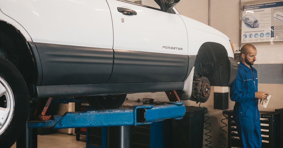Mechanic evaluating a car on a lift for maintenance in an auto workshop.